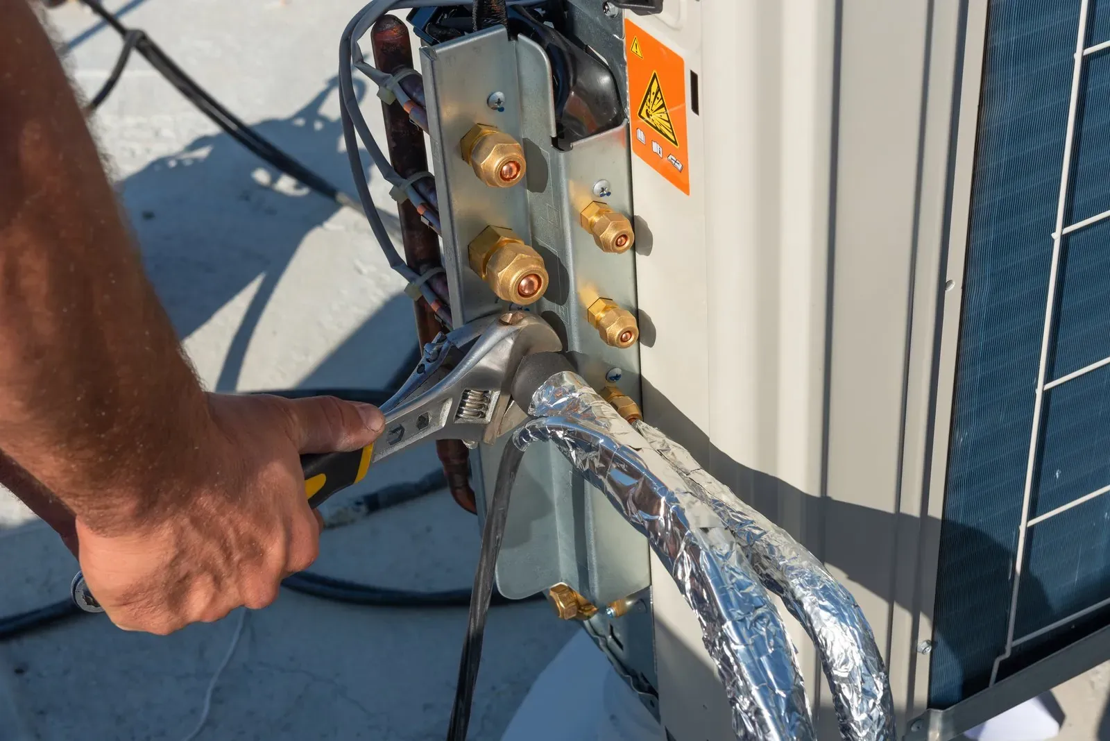 HVAC technician kneeling beside a newly installed outdoor condenser unit next to a house
