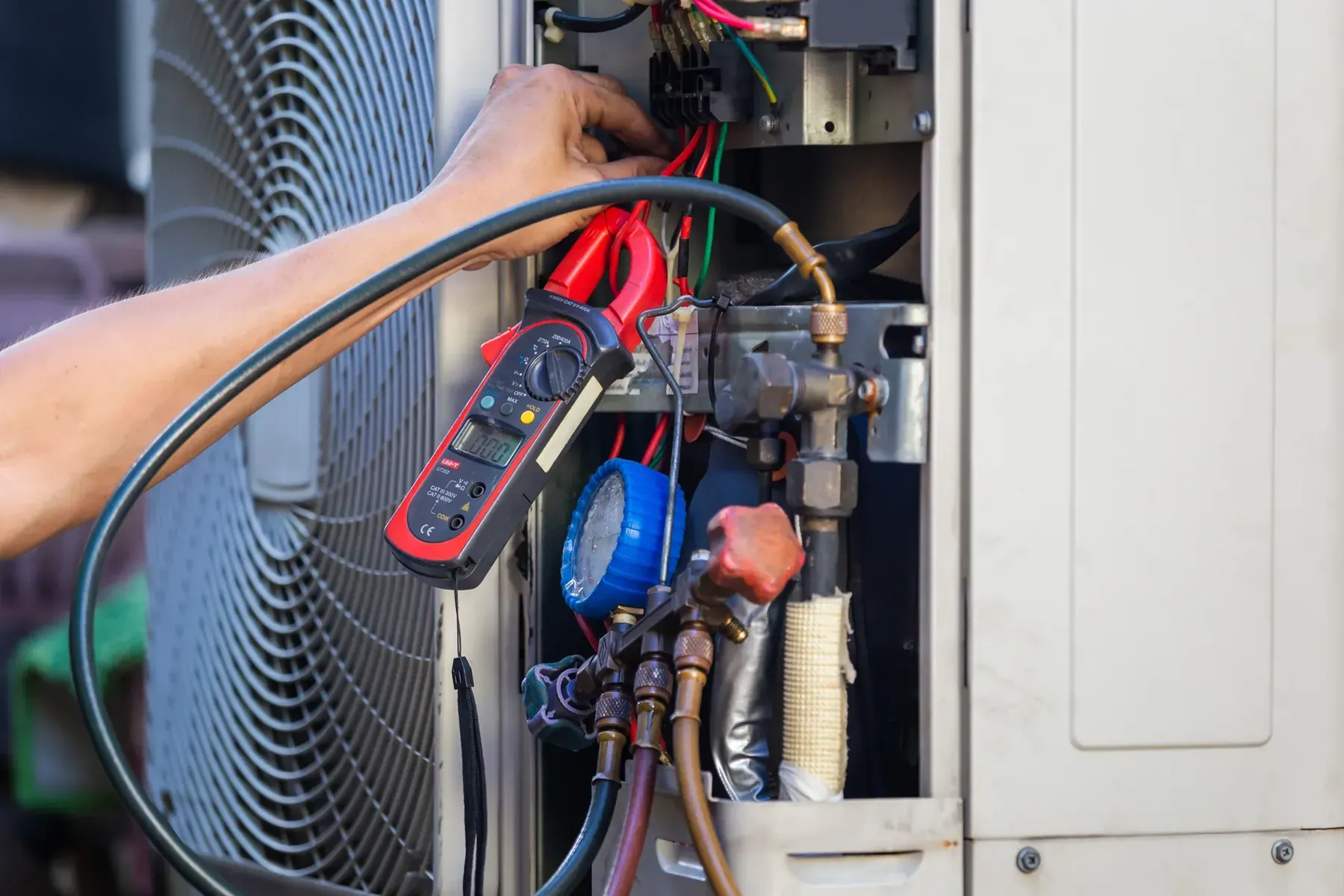 HVAC technician inspecting the refrigerant lines and service valves on an outdoor air conditioning unit