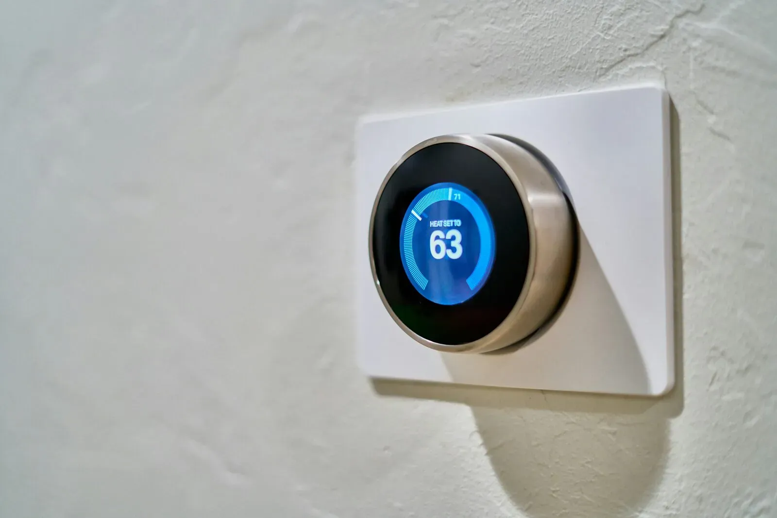 Close-up of a hand adjusting a wall-mounted home thermostat